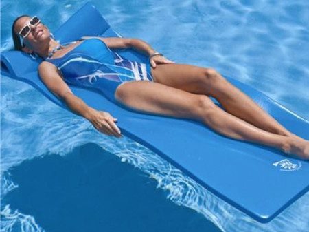A woman laying on the water in her swim suit.