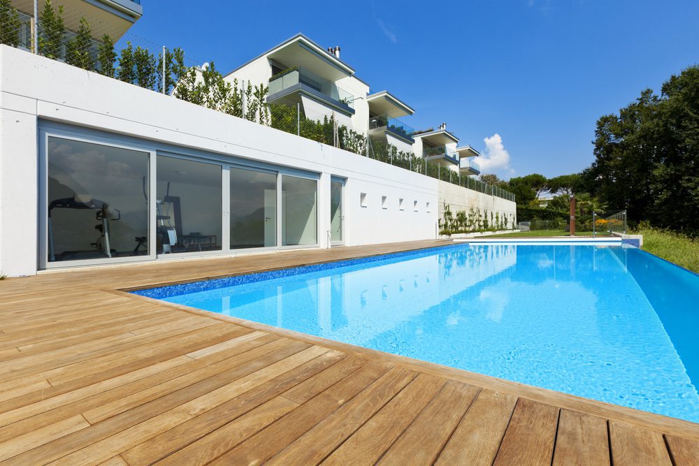 A swimming pool with wooden decking and white walls.